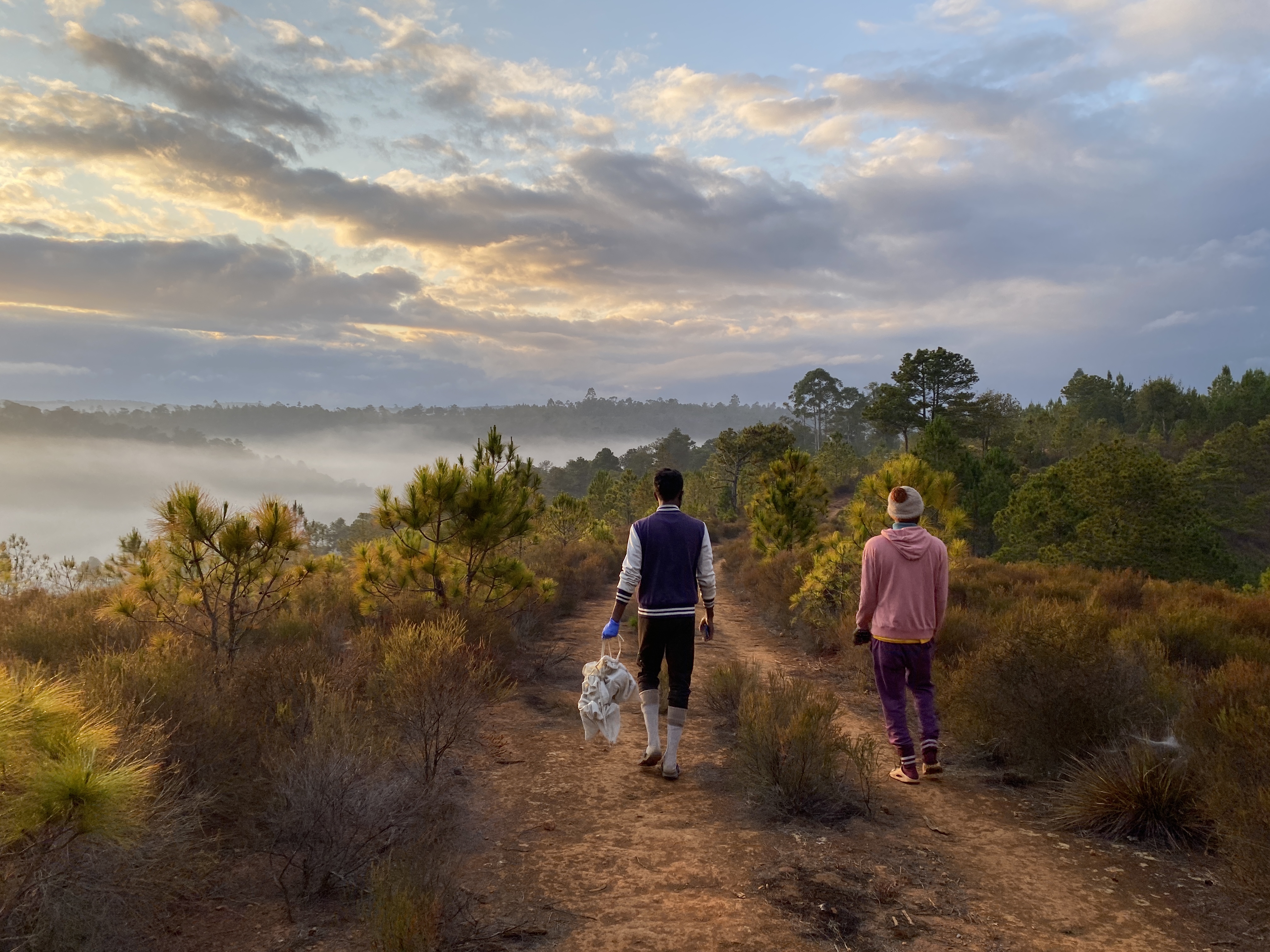 Miora and Patrick carrying bags with bats back to camp